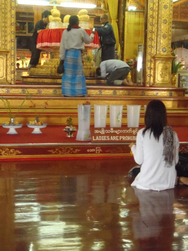 That is not a woman on the altar, that is a man wearing a longyi, the traditional attire of all Burmese people. 